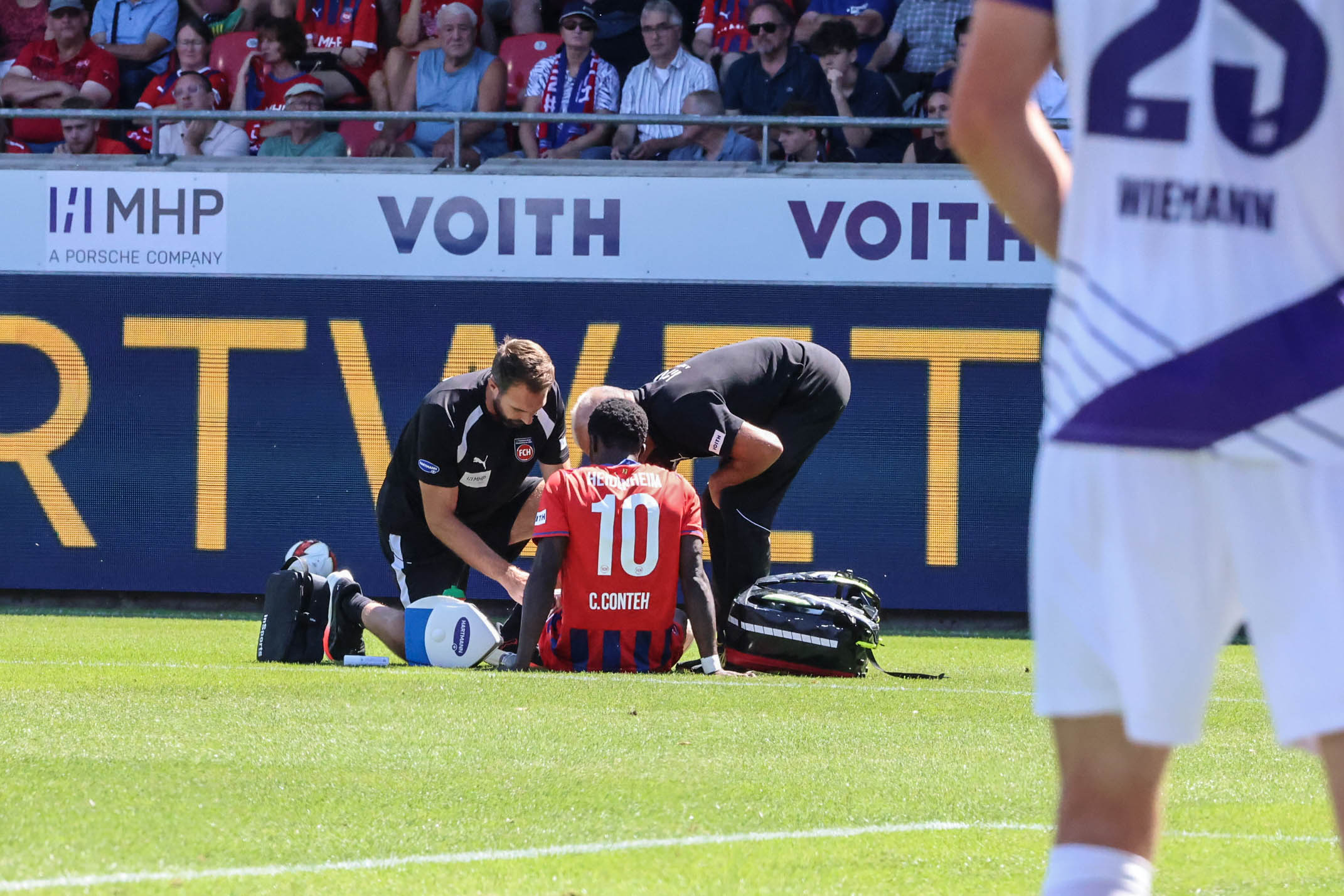 Im Einsatz: Dr. Udo Tiefenbacher, Mannschaftsarzt des 1. FC Heidenheim (rechts hinten), und Physiotherapeut Roland Bosch behandeln Christian Conteh beim Heimspiel gegen den VfL Osnabrück.