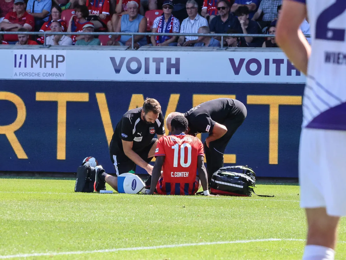 Im Einsatz: Dr. Udo Tiefenbacher, Mannschaftsarzt des 1. FC Heidenheim (rechts hinten), und Physiotherapeut Roland Bosch behandeln Christian Conteh beim Heimspiel gegen den VfL Osnabrück.