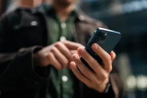 Close-up hands of unrecognizable man holding and using smartphone standing on city street, browsing internet, checking social media, using mobile application. Über eine Internetseite und eine Nachrichten-App nahm der 21-jährige mutmaßliche Täter Kontakt zu einer Sexarbeiterin auf.