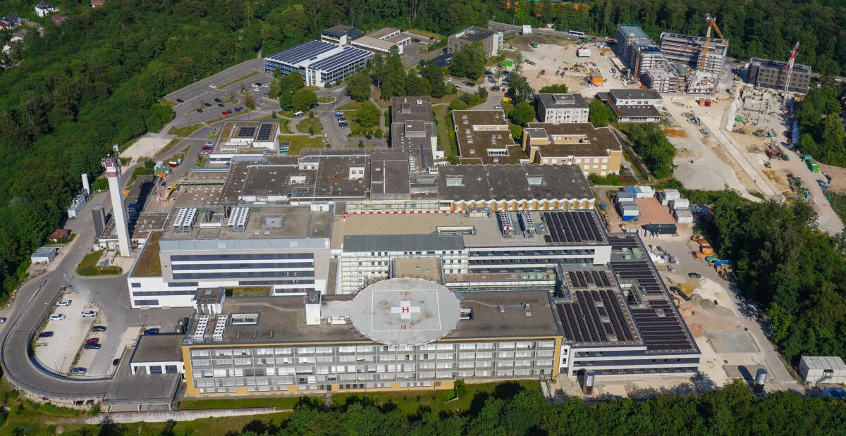 Das Klinikum auf dem Schlossberg von Westen betrachtet: Der Neubau Haus L umschließt das Haus C (im Vordergrund, mit Hubschrauberlandeplatz) und verbindet alle Gebäudeteile.