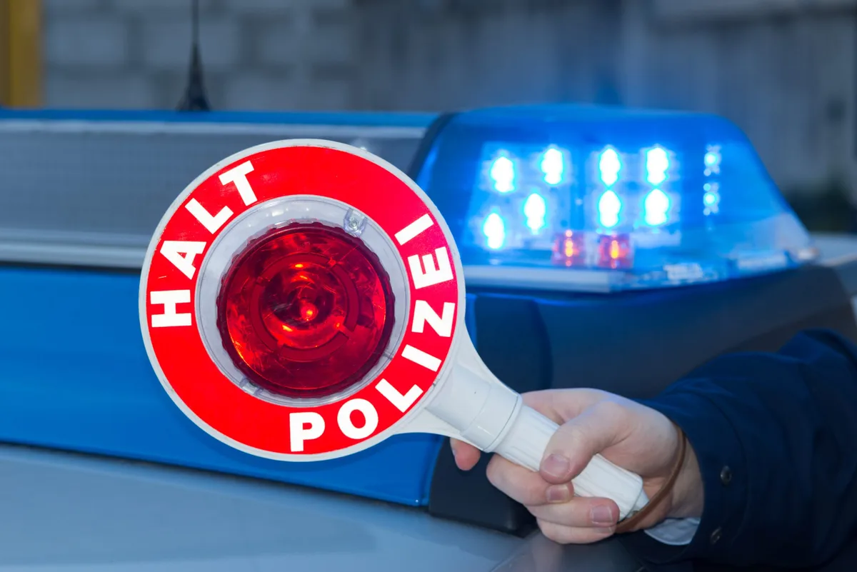 Polizeikontrolle: Ein Polizist stoppt ein Fahrzeug mit einer Polizeikelle.