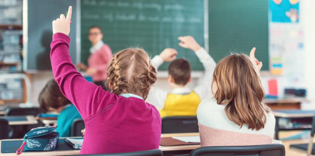 Two girl students raising hands to answer a question in school class Von den neuen Pisa-Ergebnissen waren die Schulen im Landkreis nicht überrascht.