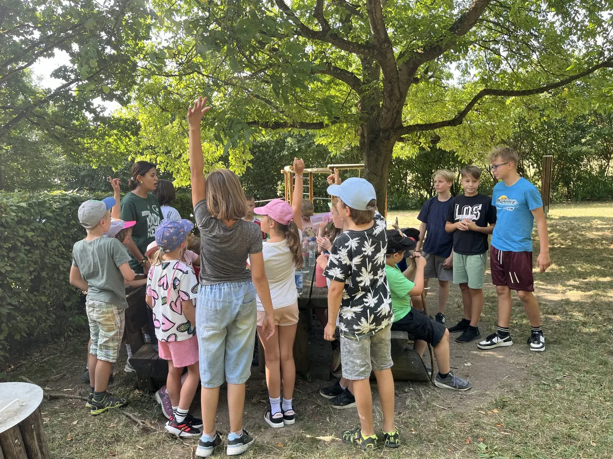 Betreuerinnen und Kinder verbringen gemeinsam Zeit auf dem Gelände des Naturfreundehauses Hasenloch.