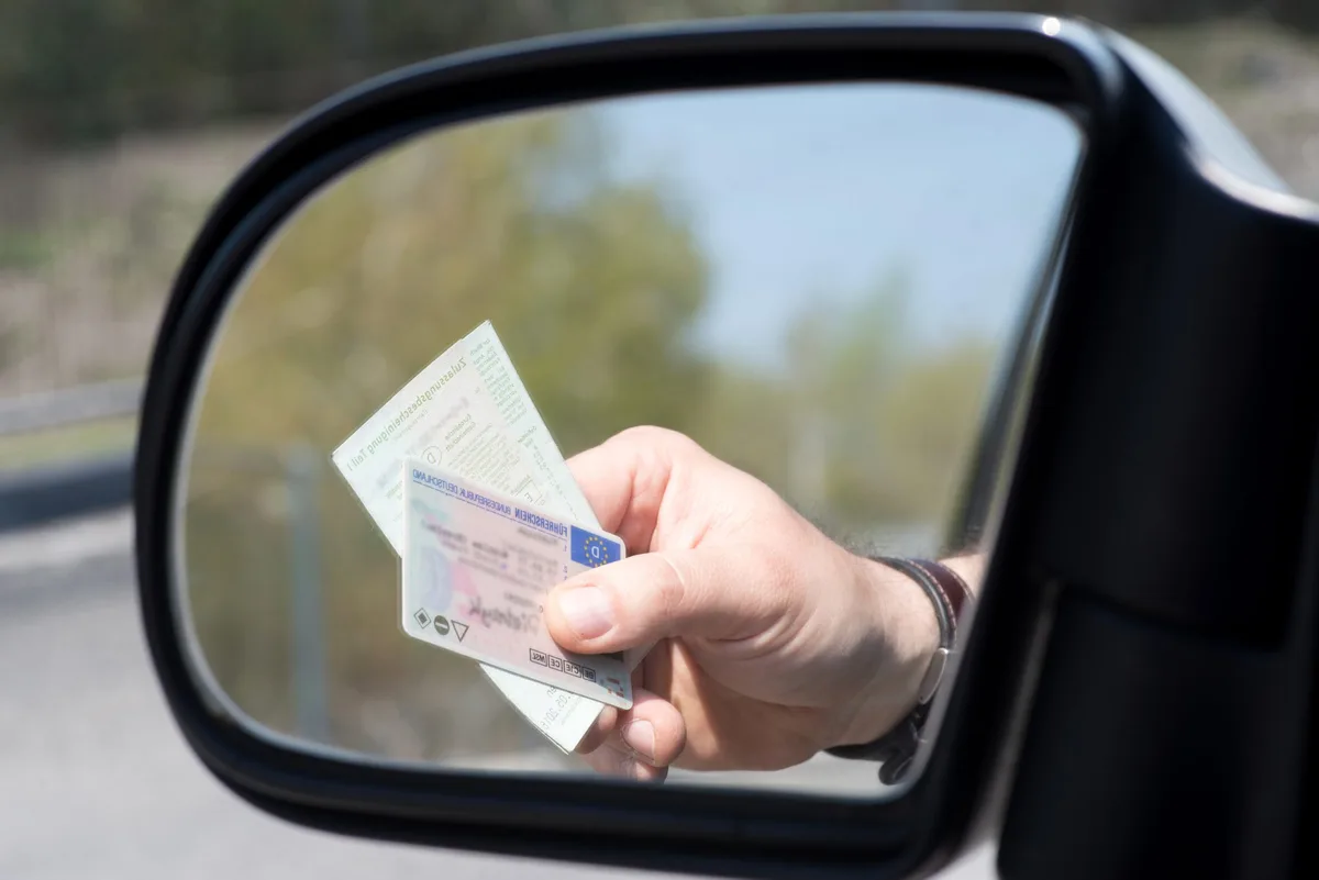Ein Mann zeigt Führerschein und Fahrzeugschein bei einer Kontrolle, Symbolfoto. Ein Mann zeigt Führerschein und Fahrzeugschein bei einer Kontrolle, Symbolfoto.