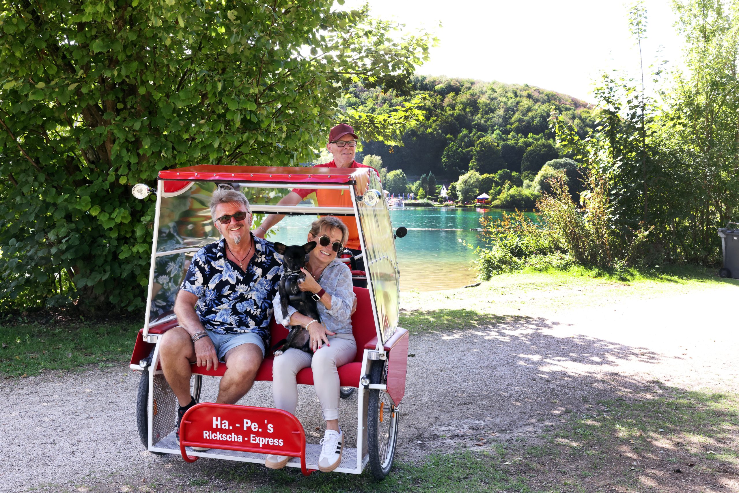 Rikscha-Fahrer Hans-Peter Brunner mit Pia und Dietmar (Diddi) Pöche, den Pächtern des Imbisses am See, und ihrem Welpen Mailo.