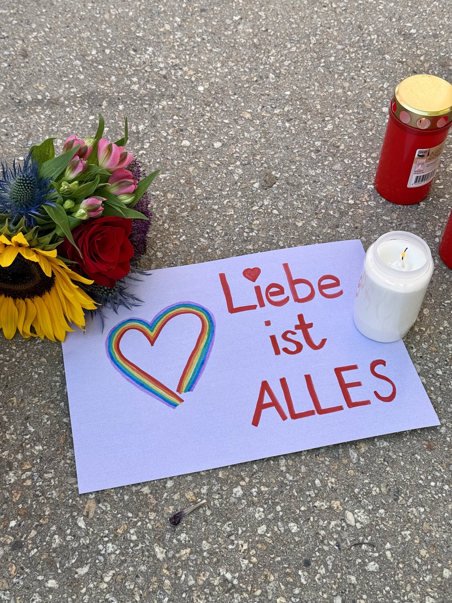 Blumen, Kerzen und ein kleines Plakat erinnern auf dem Eugen-Jaekle-Platz in Heidenheim an die Opfer des Berliner CSD-Anschlags.