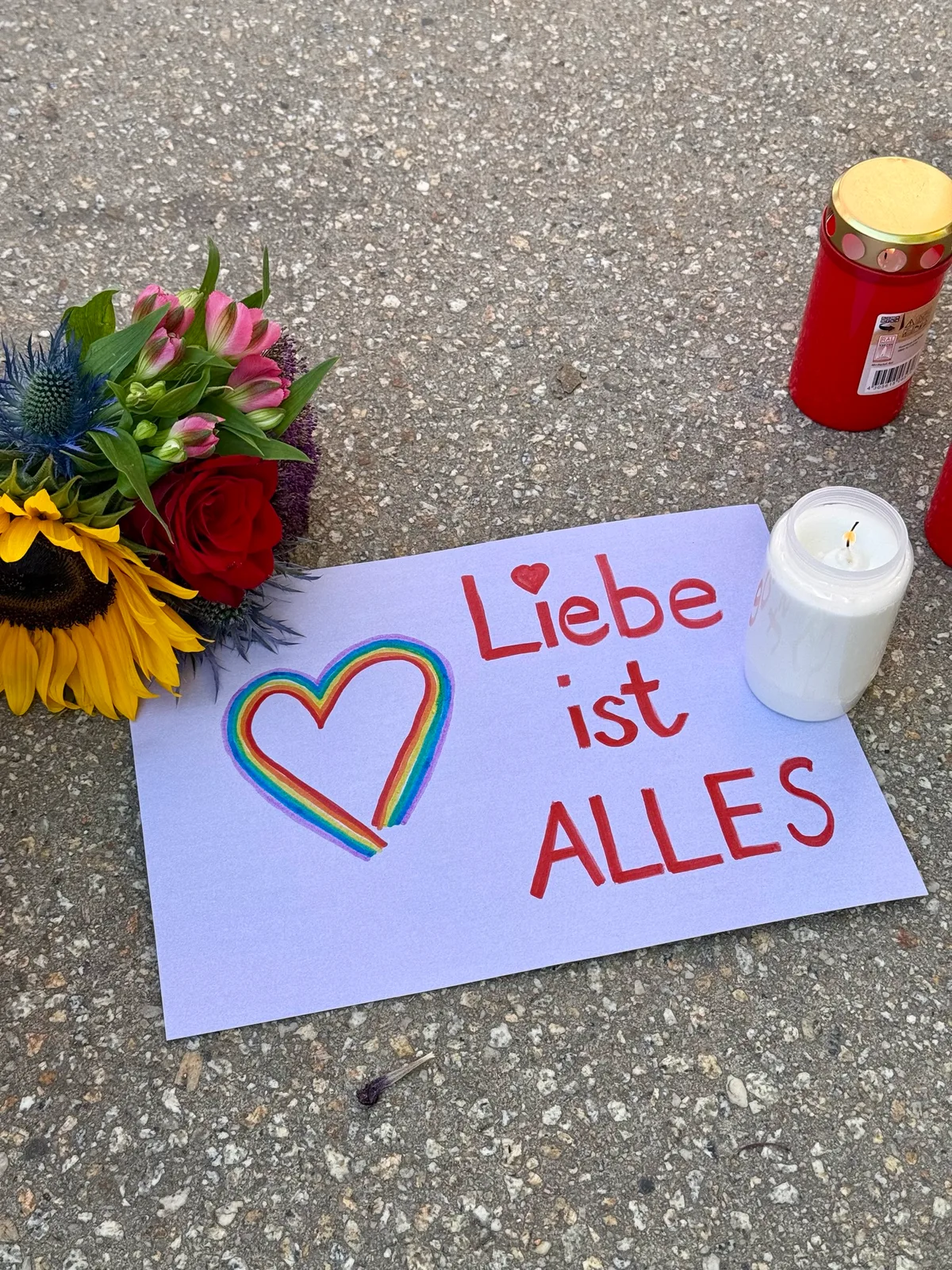 Blumen, Kerzen und ein kleines Plakat erinnern auf dem Eugen-Jaekle-Platz in Heidenheim an die Opfer des Berliner CSD-Anschlags.