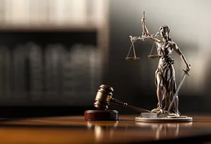 Legal Concept: Themis is the goddess of justice and the judge’s gavel hammer as a symbol of law and order on the background of books Vermutlich ist es ganz gut, dass Justitia nicht alles sehen kann.