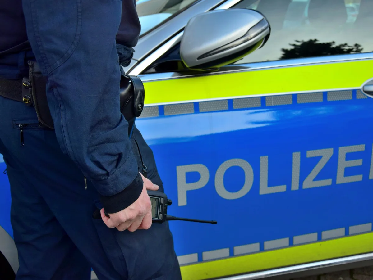 Polizist vor Streifenwagen, Symbolfoto.