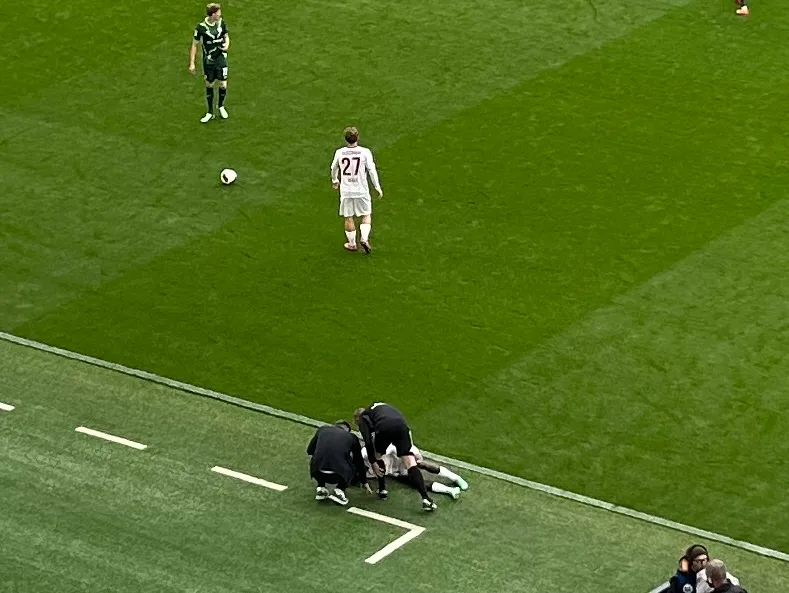Conteh Verletzungspause: Im Spiel des 1. FC Heidenheim beim VfL Wolfsburg blieb Christian Conteh auf dem Rasen liegen. Wolfsburgs Trainer Tobias Strobl (links) und der vierte Offizielle Robert Wessel kamen zu Hilfe.